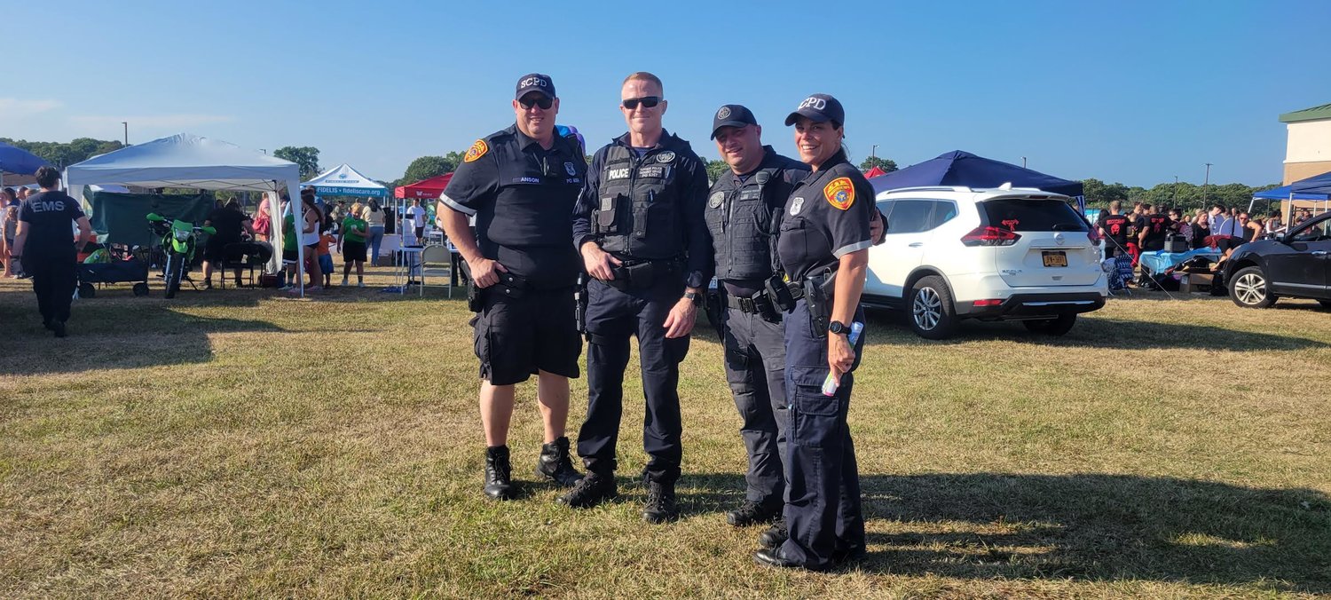 James Anson, a community-oriented police engagement (COPE) officer for the Seventh Precinct (left); Philip Archer, emergency service officer (center left); Frank Munsch, emergency service officer (center right); and Heidi Cummings, police officer at the Seventh Precinct, enjoying National Night Out in the William Floyd High School field.